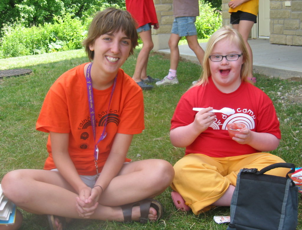 Kids to Camp Grant Image, camp councilor sitting on the grass with a camper