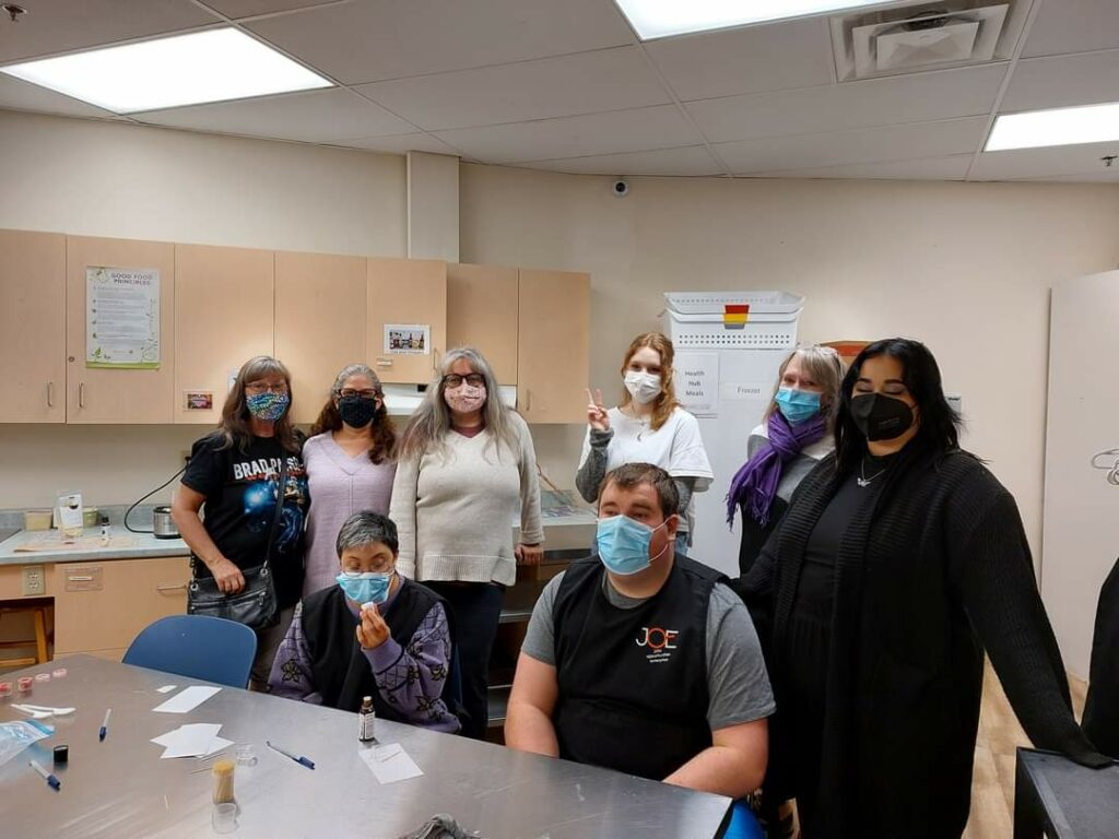 Photo of eight masked adults in a kitchen posting for the camera