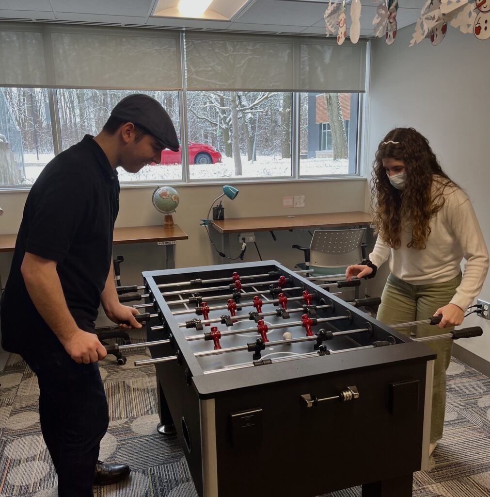 Two young people playing foosball in a casual setting