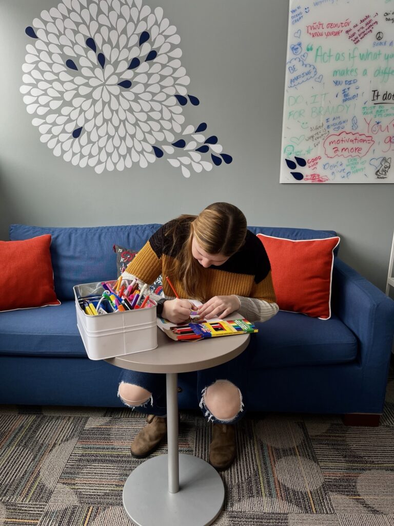 Young person colouring with pencil crayons in a living room setting
