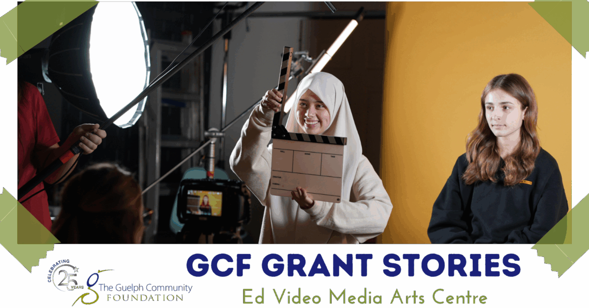 Person in a white hoodie holding a film clapperboard in a video production studio with professional lighting and camera setup.