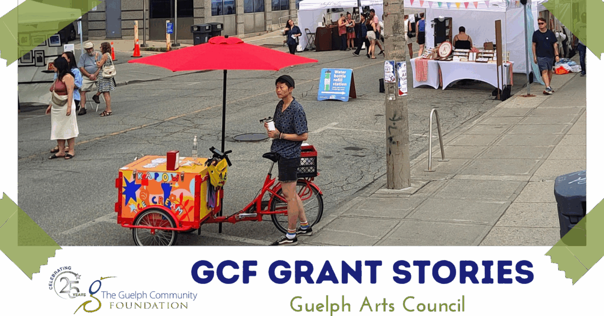 Person standing beside a colorful ice cream cart with a red umbrella at an outdoor street market event.