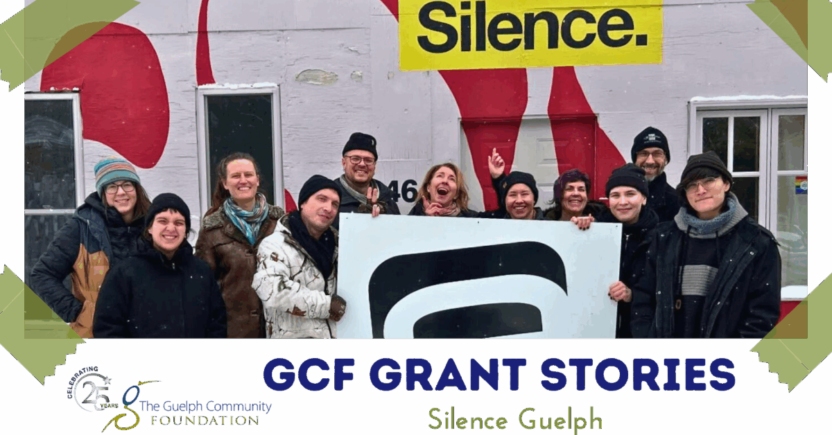Group of people standing outdoors in winter clothing holding a large sign with a bold black symbol in front of a wall painted with red shapes and the word 'Silence.'