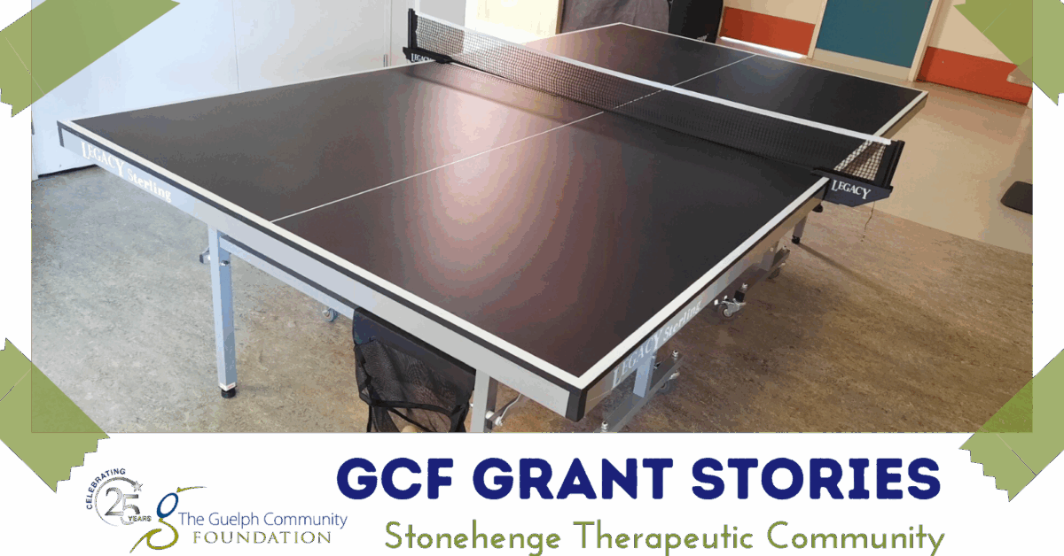 Black Legacy Sterling ping pong table set up indoors with net and ball basket underneath on wheels.