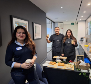 Photo of three people holding coffee cups behind the barista bar