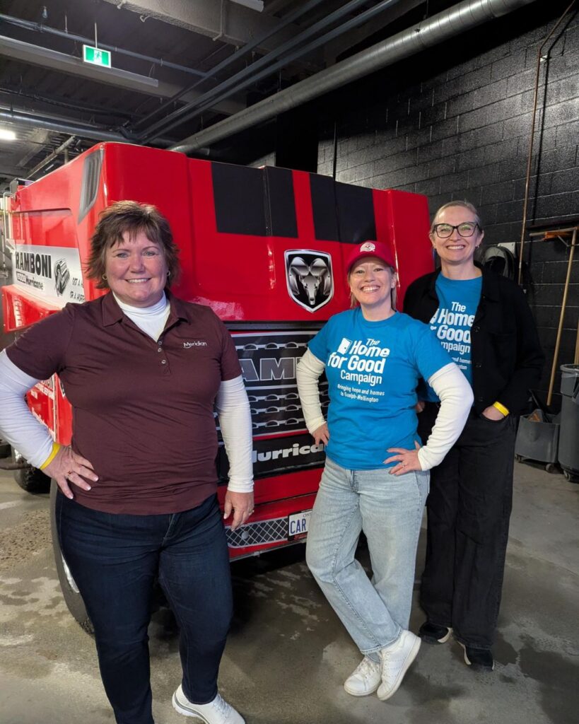 Sarah, Glenna and Terri standing in front of a large red Ram-boni inside the arena's garage