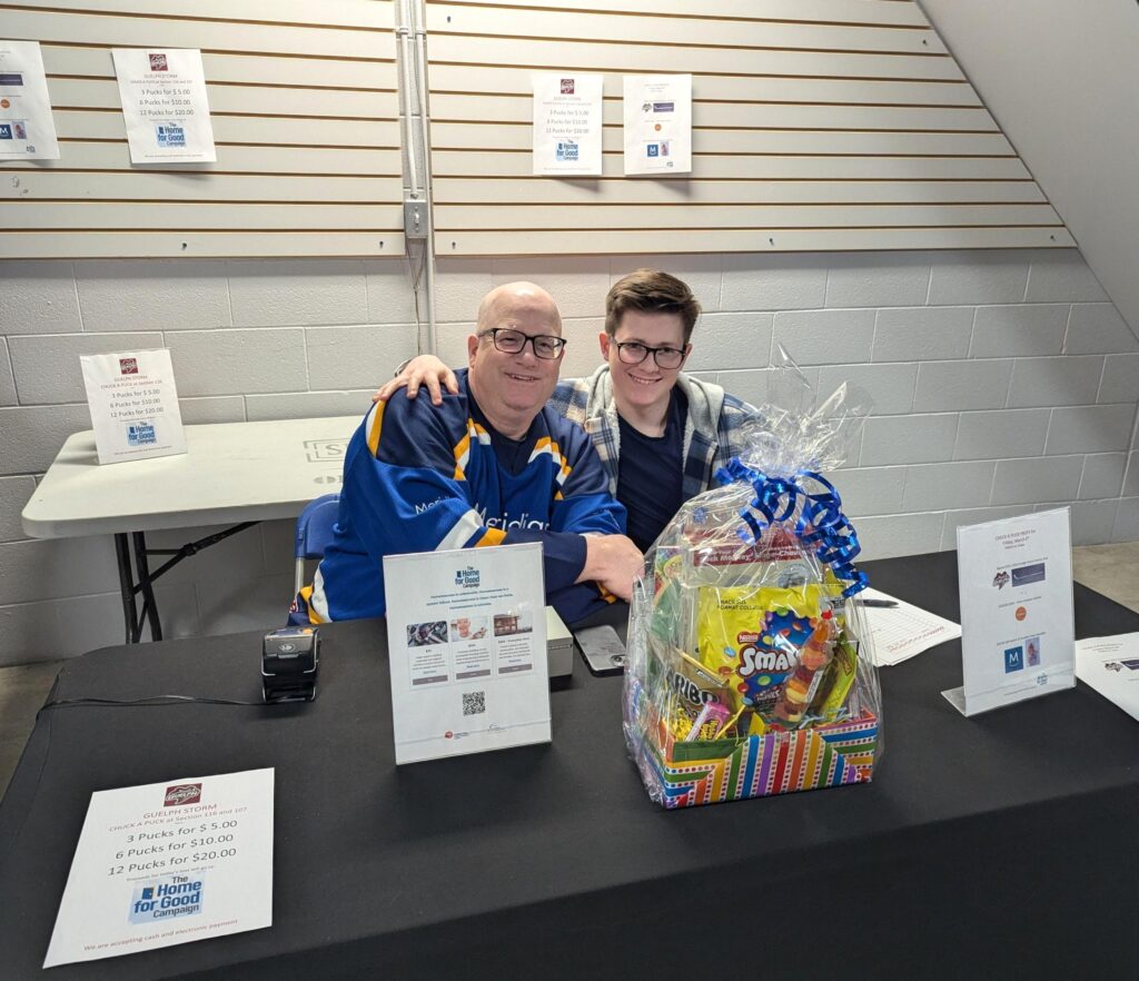 Two volunteers at a prize table selling Chuck-a-pucks and taking donations.