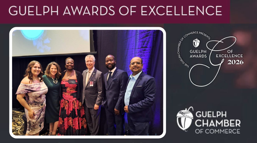Group of six people dressed formally posing together at an indoor event with a projection screen and purple lighting in the background. Text reads Guelph Awards of Excellence with the logos
