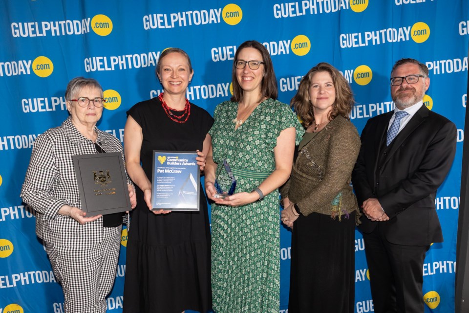 Five individuals stand in front of a blue GuelphToday.com backdrop, three women holding awards and two others posing formally.