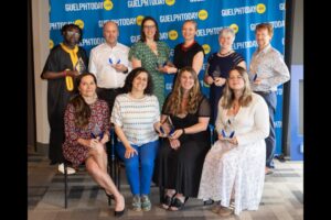 Group of eleven people posing with awards in front of a GuelphToday.com backdrop at an indoor event.