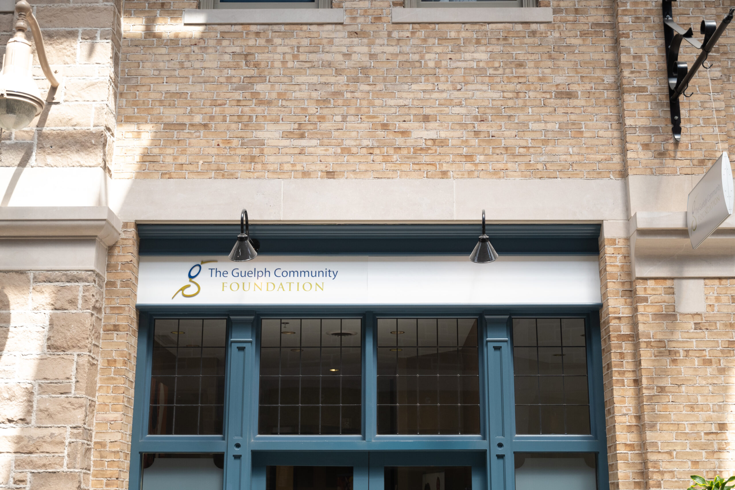 Entrance of The Guelph Community Foundation with a blue-framed glass door set in a beige brick building.