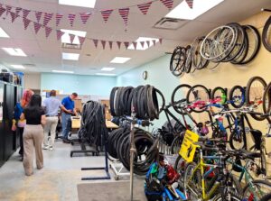 The bike repair area with multiple bicycles, tires, and wheels displayed on racks, with the staff walking by in the library