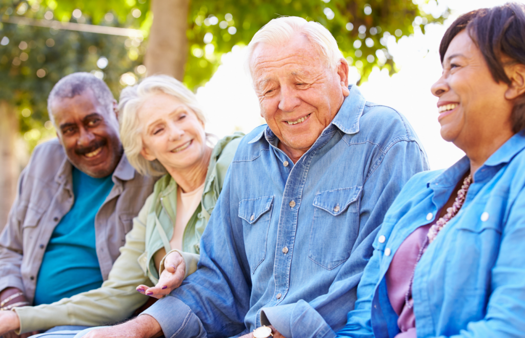 A group of diverse elders chatting and laughing in an outdoor setting.