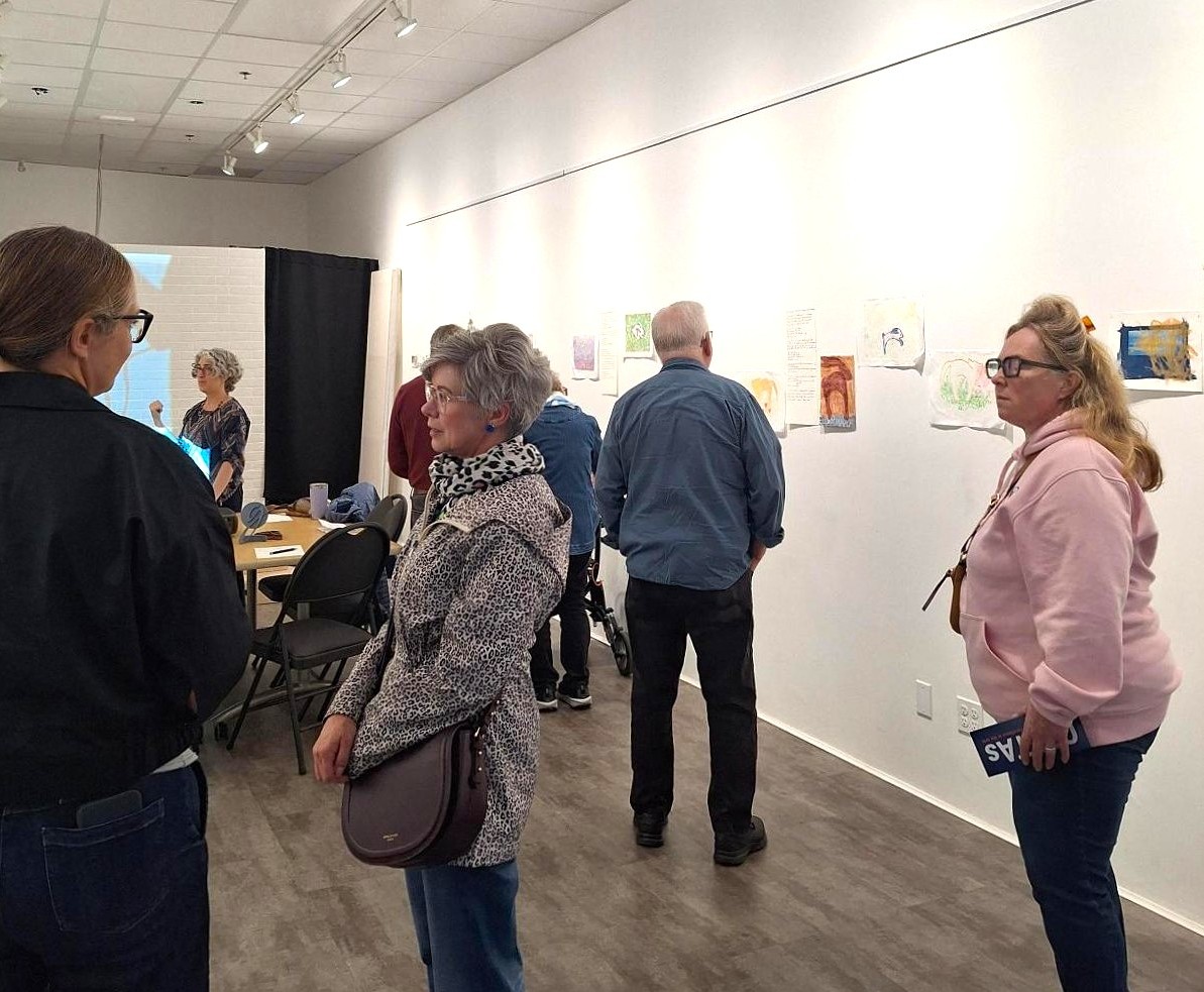 Adults engaged with artwork displayed on white walls in a modern gallery space.