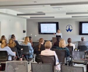A speaker presents to attendees during a workshop on building effective partnerships, with presentation slides displayed on screens at the front of the room.