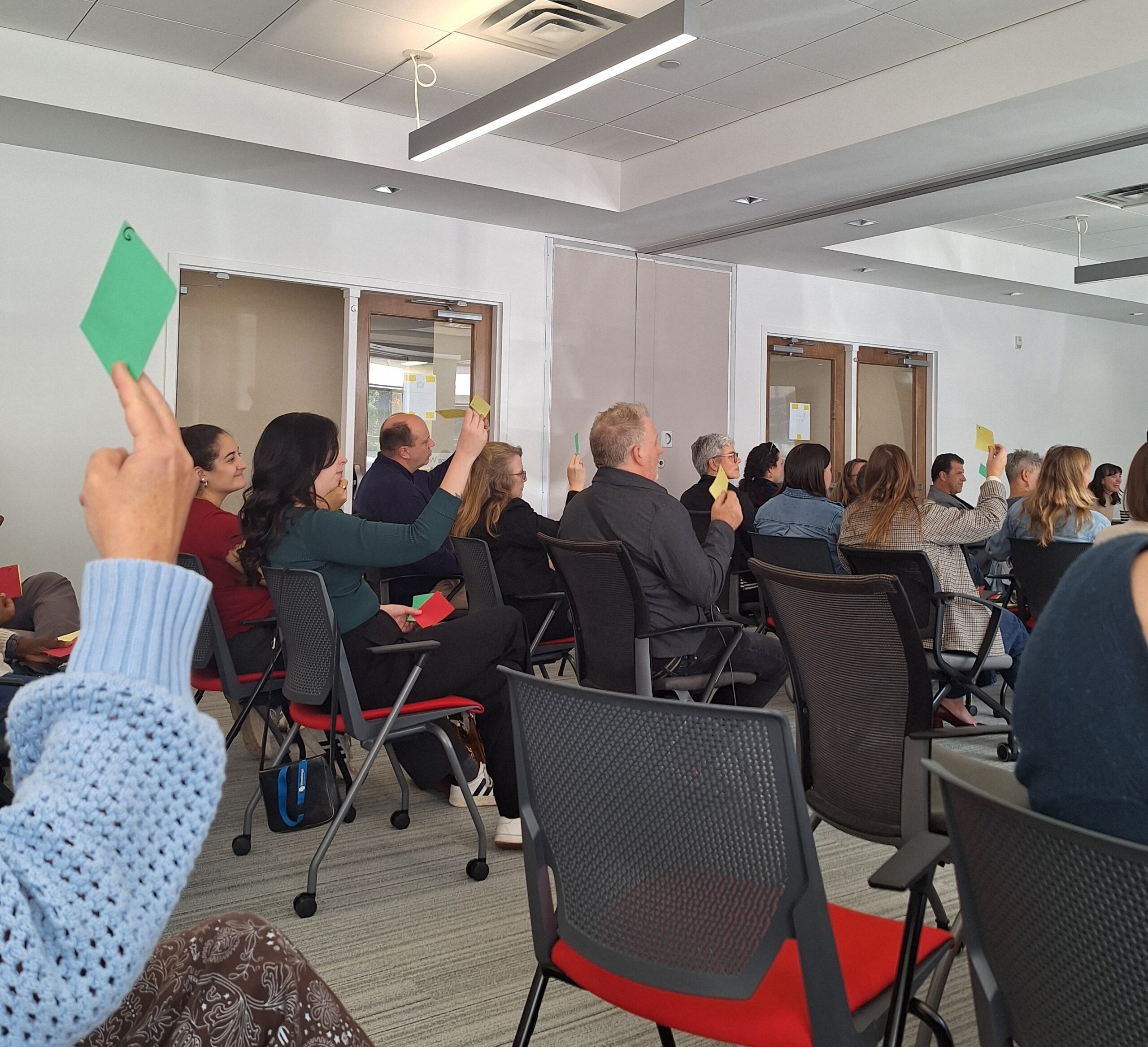 Attendees raise coloured cards to participate in an interactive audience activity during a workshop session at the Finding Abundance symposium.