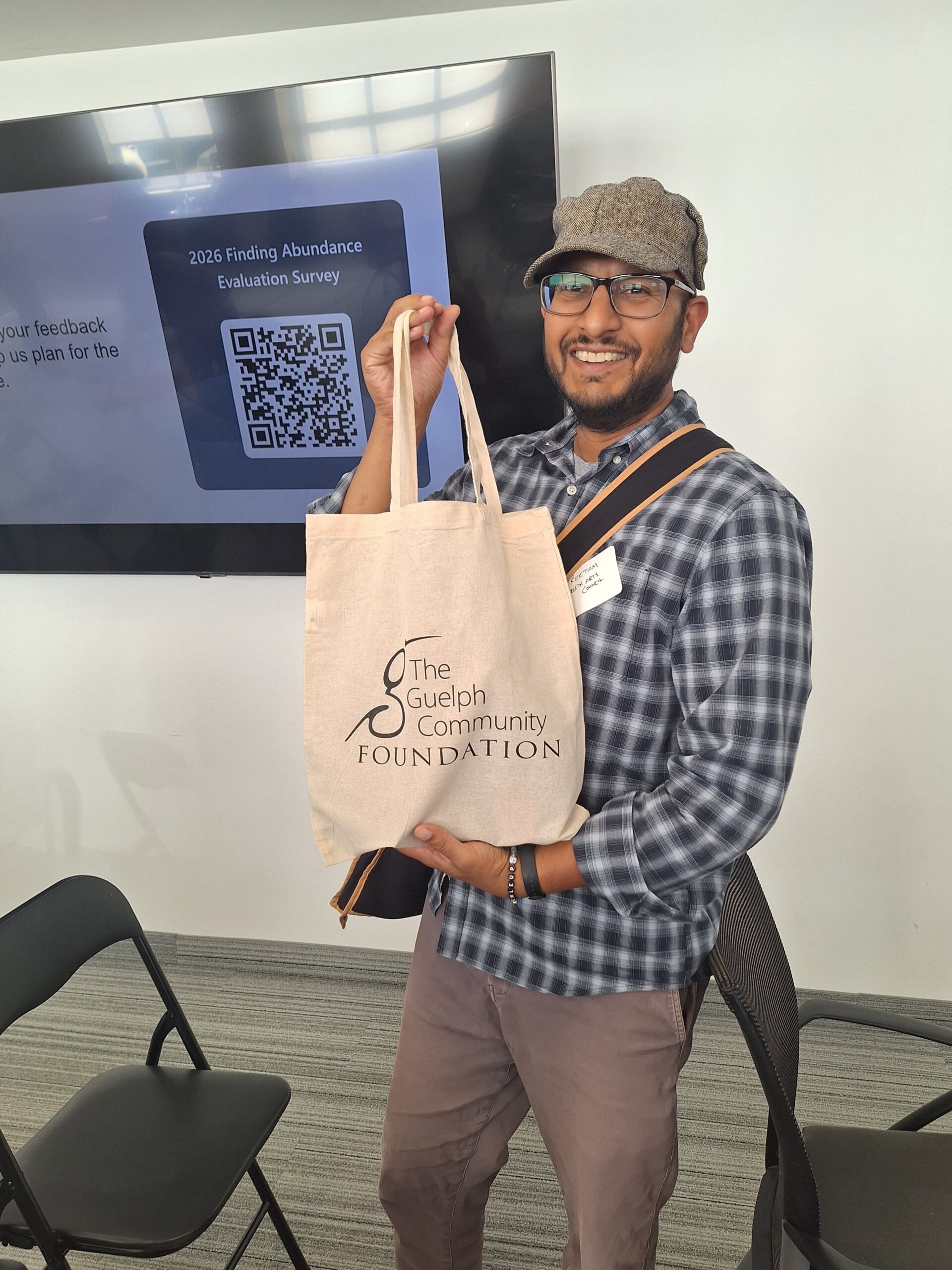 An event participant holds up a Guelph Community Foundation tote bag as their door prize from the Finding Abundance symposium.