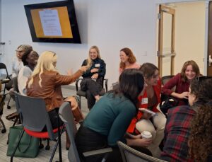 Attendees engage in conversation and laughing in small circles during a networking exercise at the Finding Abundance symposium.