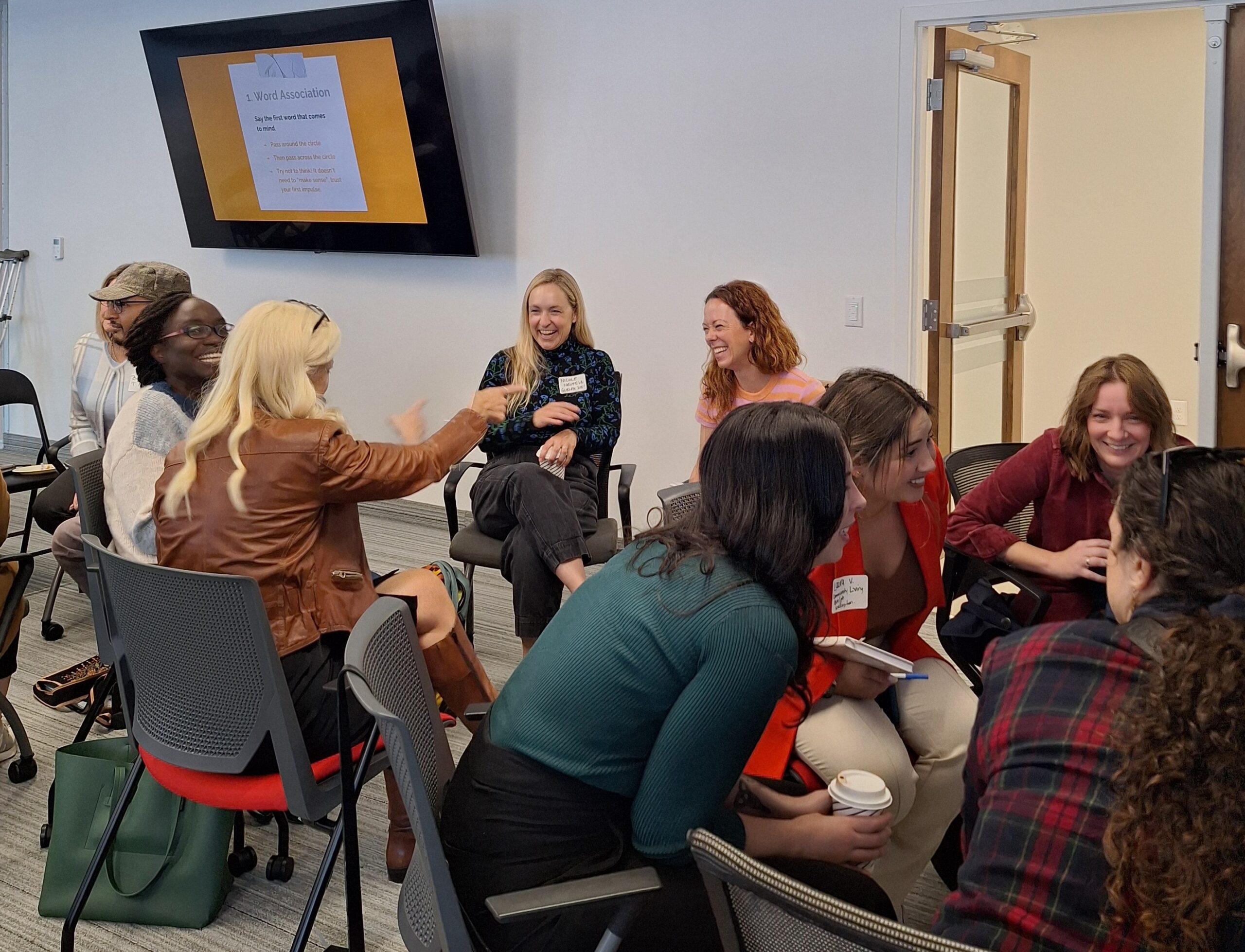Attendees engage in conversation and laughing in small circles during a networking exercise at the Finding Abundance symposium.