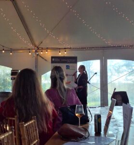 A female speaker stands inside a tent with a microphone