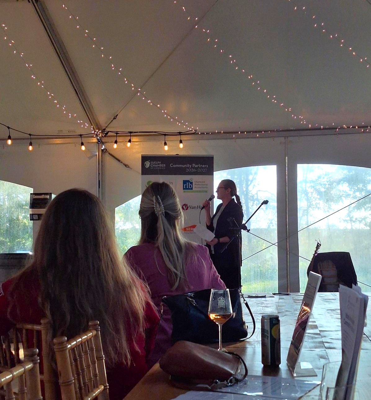 A female speaker stands inside a tent with a microphone