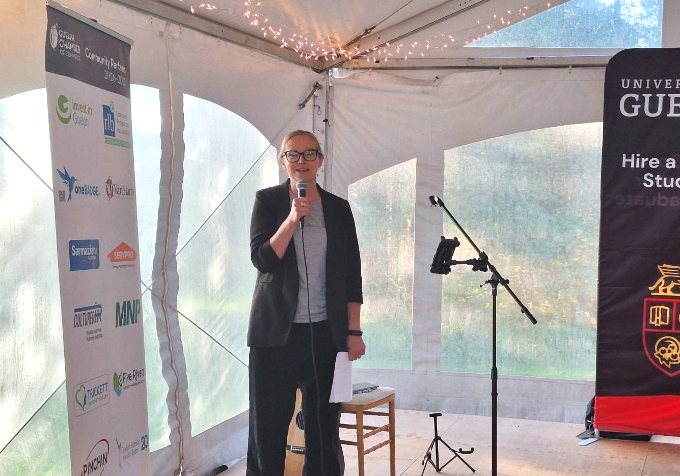 A female speaker stands inside a tent with a microphone